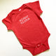 red baby boy onesie with white lettering that says mister aloha