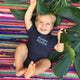 baby boy on a colored rug wearing a navy blue baby onesie with white lettering that says mister aloha