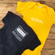 gold yellow and navy blue gender neutral baby Ivy & Co. onesie with white writing that says aloha